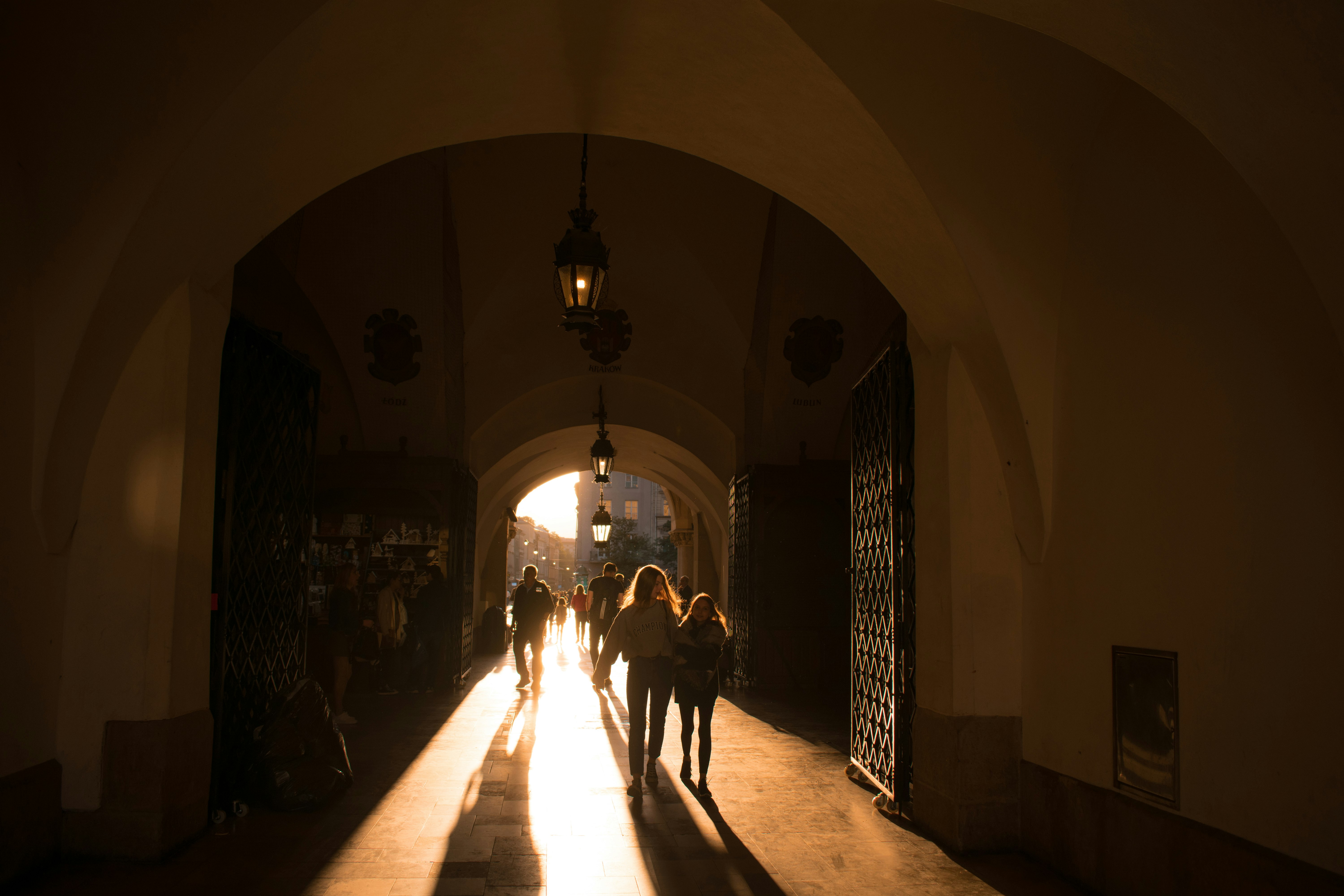 people walking on hallway with lighted chandeliers